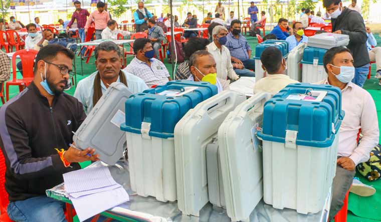 Election officials check Electronic Voting Machine (EVMs) after collecting it from a distribution centre on the eve of by-polls at Raisen district | PTI