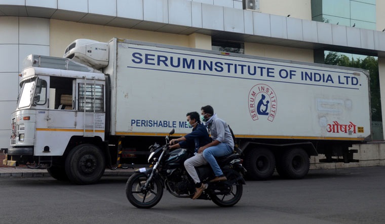 Men ride on a motorbike past a supply truck of Serum Institute in Pune | Reuters