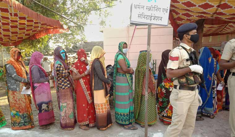 Women stand in a queue to cast their votes during the Madhya Pradesh Assembly bypolls, amid the ongoing coronavirus pandemic, in Indore district | PTI