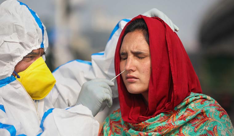 A health worker collects a nasal sample from a woman for COVID-19 test, in Jammu | PTI