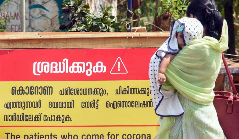 A woman with her child walks past a notice board outside Special Isolation Ward set up to provide treatment to novel coronavirus patients at a hospital in Kochi | PTI