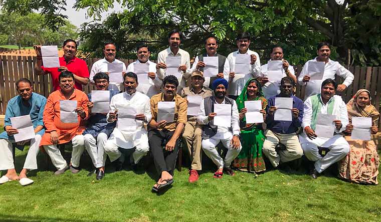 MLAs of the ruling Congress in Madhya Pradesh show their resignation letter as they pose for a group photo, in Bengaluru | PTI