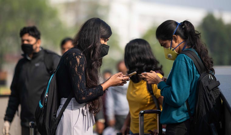 Women wearing facemasks as a preventive measure against the COVID-19 coronavirus use their mobile phones outside a metro station in New Delhi | AFP