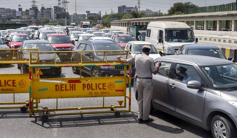 A police official checks ID cards of commuters on the Gurgaon-Delhi border | PTI