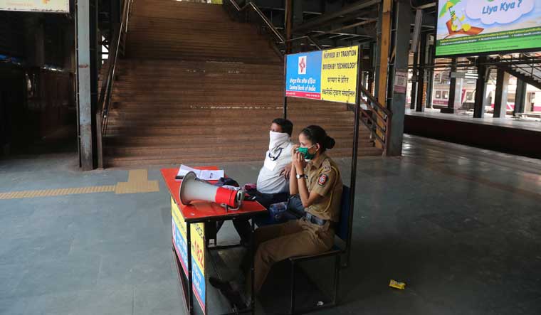 Police officers wearing masks sit at a deserted railway station in Mumbai | AP