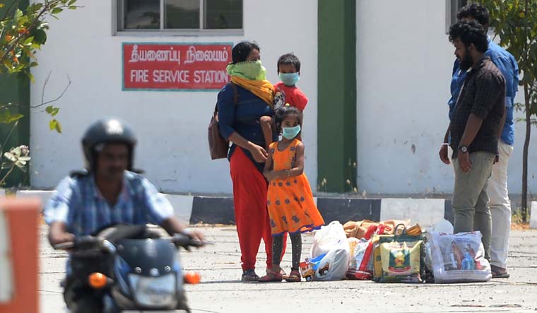 Stranded travellers stand with their belongings at the Tamil Nadu-Andra Pradesh interstate border along a national highway during a government-imposed lockdown | AFP