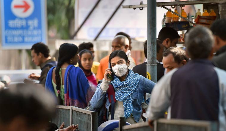 A young woman wearing a protective mask in the wake of novel coronavirus outbreak speaks on the phone at RML Hospital in New Delhi | PTI