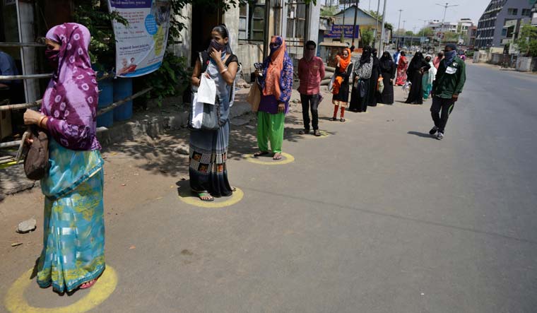 People stand in queue outside a fair price shop during lockdown, in Ahmedabad | AP