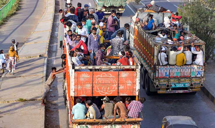 Migrants travel in a truck to their native villages in Uttar Pradesh, in Prayagraj | PTI