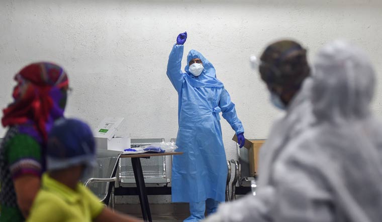 A medic wearing protective gear gestures during medical screening of residents for COVID-19, at Dadar in Mumbai | PTI