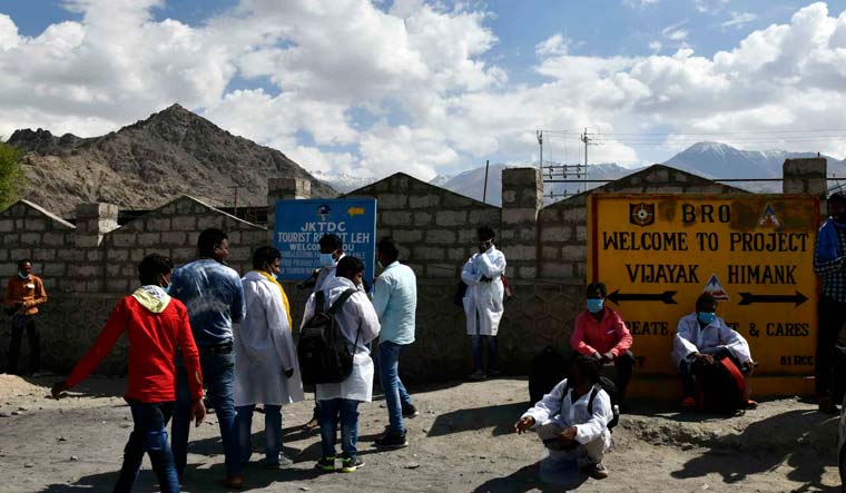 People waiting near a sign showcasing two projects of the Border Roads Organisation, Vijayak and Himank | Sanjay Ahlawat/Leh, Ladakh