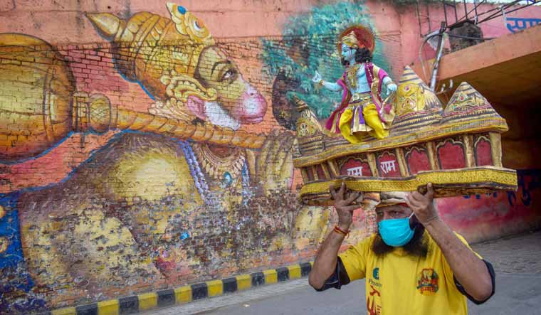 Prayagraj: A worker carries a model of Ram Mandir on his head on the eve of the foundation stone laying ceremony of the temple in Ayodhya, in Prayagraj, Tuesday, Aug 4, 2020 | PTI 