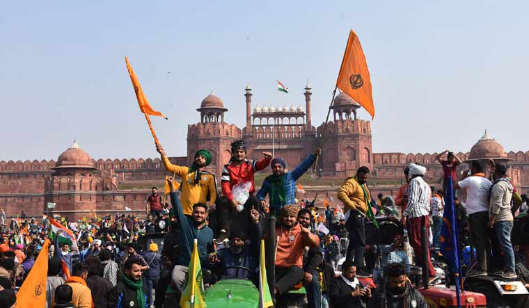 Sikhs wave the Nishan Sahib, a Sikh religious flag, as they arrive at the historic Red Fort monument in New Delhi on Tuesday | AP