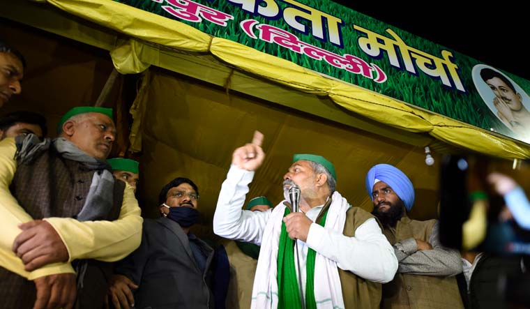 BKU spokesperson Rakesh Tikait speaks as Ghaziabad DM Ajay Shankar Pandey (seen at back wearing mask) looks on at the site of farmers' ongoing protest against the new farm laws at Delhi-Ghazipur border | PTI