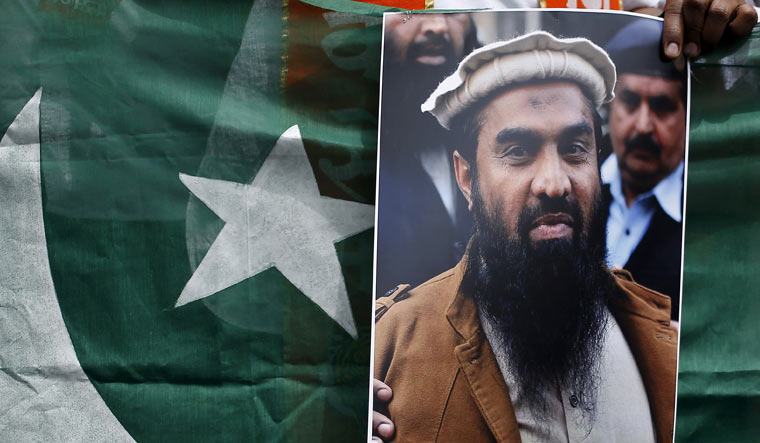 [File] A supporter of Shiv Sena holds Pakistan's national flag and a portrait of Zaki-ur-Rehman Lakhvi during a protest against his release, in New Delhi on April 11, 2015 | Reuters