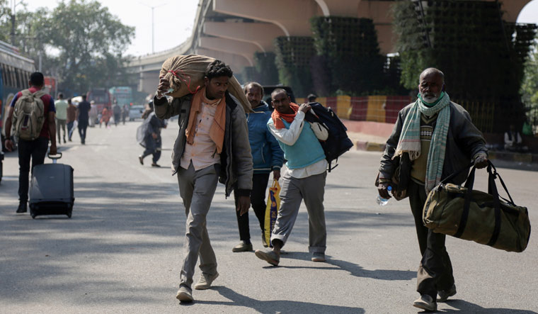 [File] Migrant laborers carry their luggage and walk towards a bus station as they leave for their homes in Jammu | AP