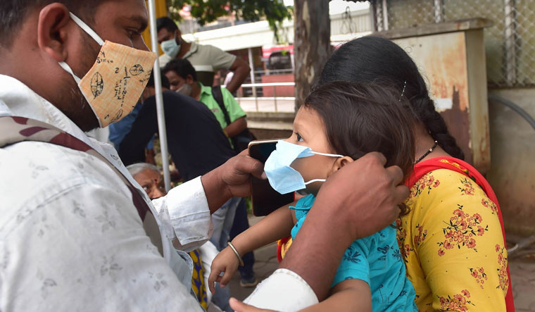 A man helps his son to wear mask at a COVID-19 test centre at KSRTC bus stand in Bengaluru | PTI