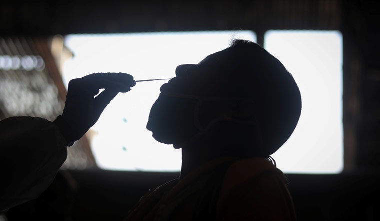 A health worker collects swab sample from a man during a rapid antigen testing drive in Mumbai | Reuters