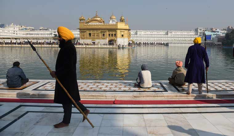 Sikh guards stand holding spears as devotees arrive to worship at the Golden Temple | PTI
