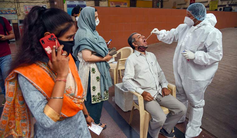 A medic takes swab sample from a passenger for Covid-19 test amid surge in coronavirus cases, at Kopar Khairane Railway Station, in Navi Mumbai | PTI