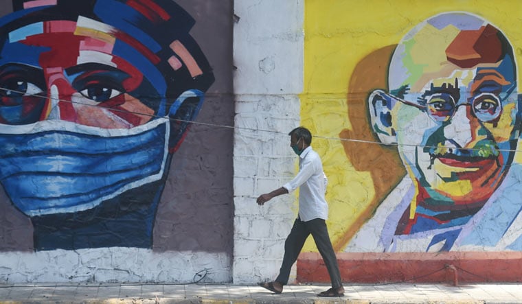 A pedestrian walks past a wall mural in Mumbai | PTI