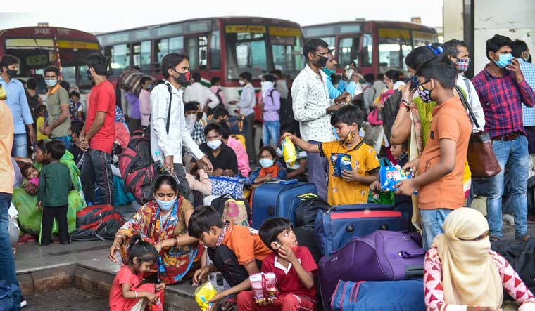 Migrants wait to board a bus after UP Government imposed restrictions in view of surge in coronavirus cases, at Alambagh Bus Station in Lucknow | PTI