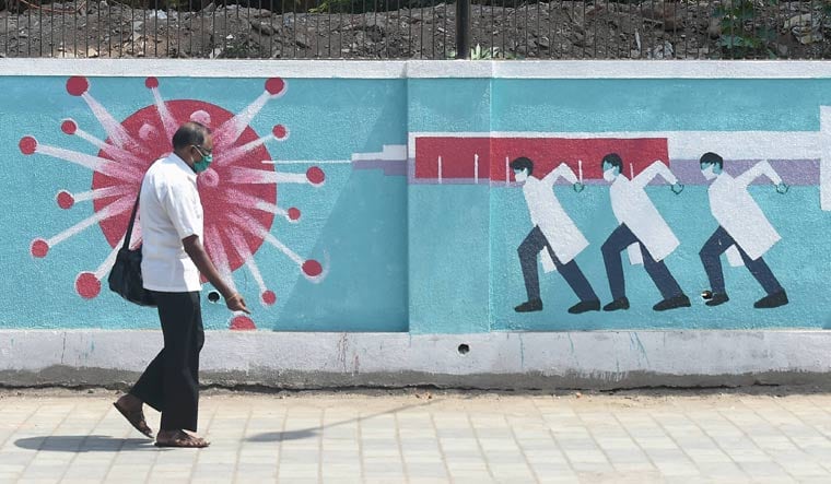 A man walks past a graffiti depicting coronavirus in Mumbai | PTI