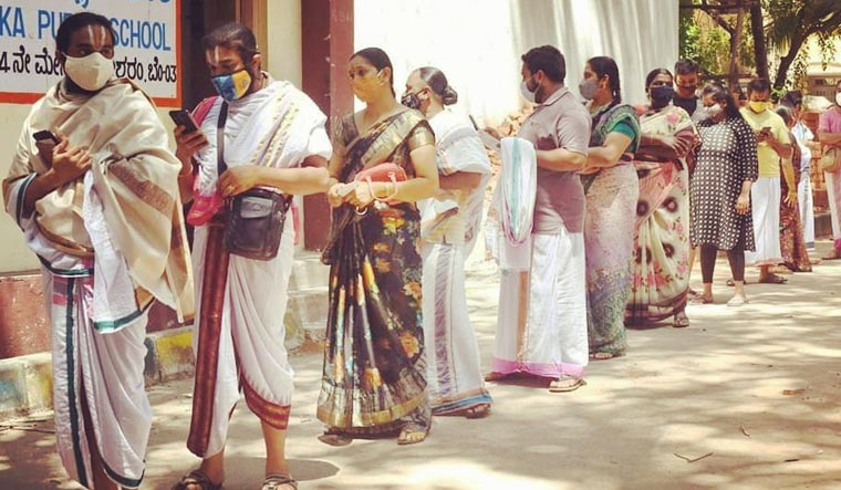 Priests and their family members stand in queue to receive the jab at a vaccination centre in Malleswaram in Bengaluru.