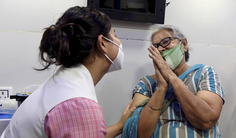 A beneficiary folds hands in gratitude to a health worker before receiving a dose of COVID-19 vaccine, at a Mobile vaccination centre in New Delhi | PTI