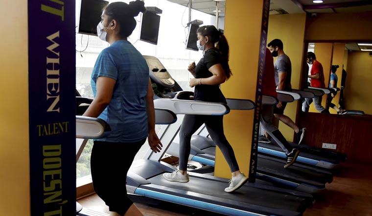 Fitness enthusiasts workout in a gym that reopened after authorities eased COVID-induced restrictions, in New Delhi | PTI