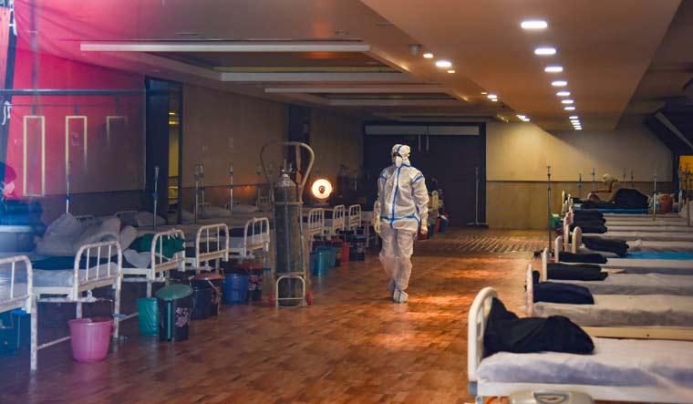A health worker walks inside the Shehnai Banquet Hall, a COVID-19 care facility, in Delhi | PTI