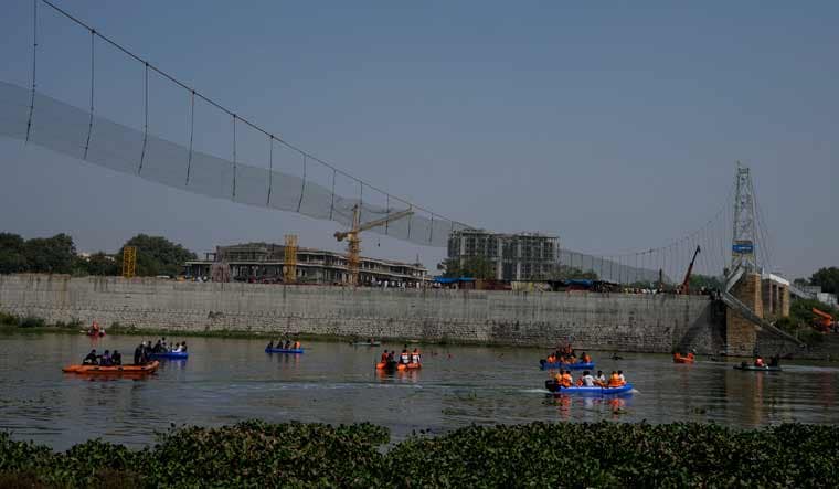 Rescuers on boats search in the Machchu river next to a pedestrian bridge that collapsed in Morbi  | AP