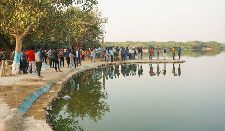 Media personnel and locals near a pond where Aftab Poonawala, accused in Mehrauli murder case, is suspected to have dumped his live-in partner Shraddha Walkar's remains in Delhi | PTI