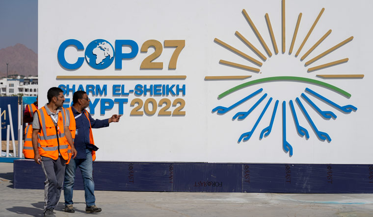 Workers pass a sign at the convention center hosting the COP27 U.N. Climate Summit | AP