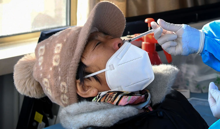 A woman receives the booster dose of Covid-19 vaccine through the nose, at a temporary vaccination site in Beijing | AP