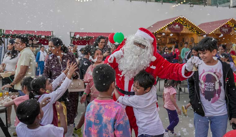 Children play with a man dressed as Santa Claus during a Christmas Carnival, at Jio World Drive in Mumbai | PTI