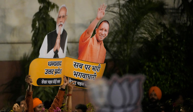 BJP supporters hold cuts outs of Prime Minister Narendra Modi and Uttar Pradesh Chief minister Yogi Adityanath as they celebrate at the party headquarters in New Delhi | AP