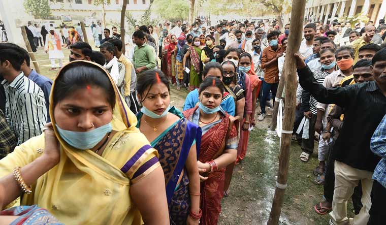 Citizens wait to cast their vote outside a polling booth in Varanasi | PTI
