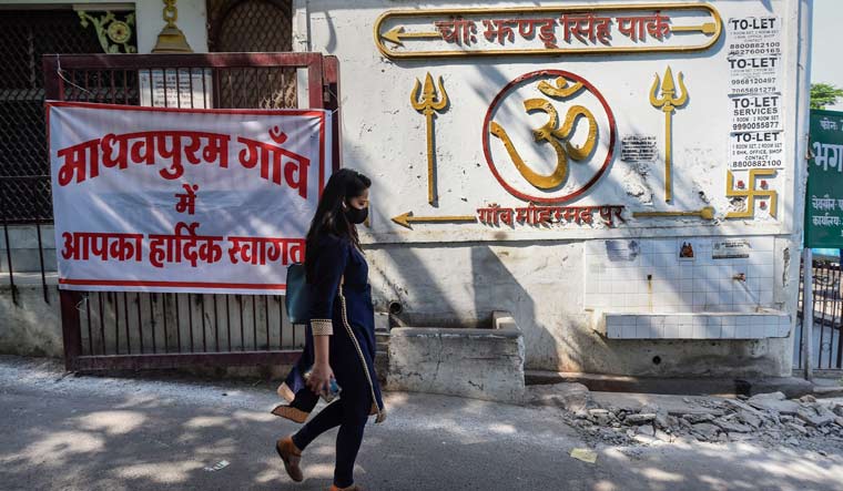 A woman walks past a board with the message 'Welcome to Madhavpuram'  after the village Mohammadpur was renamed to 'Madhavpuram' | PTI