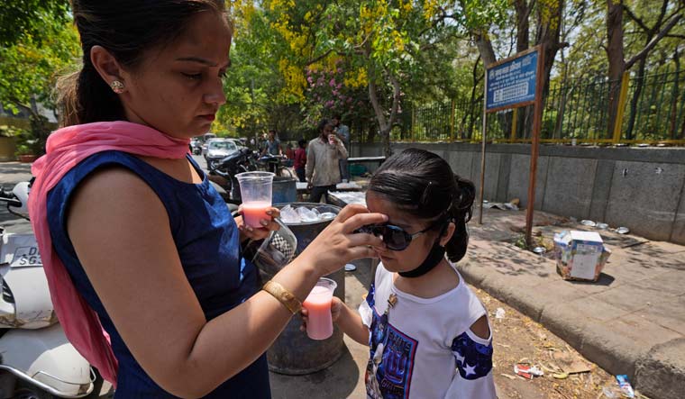 A woman puts on a sunglass for her child in New Delhi | AP