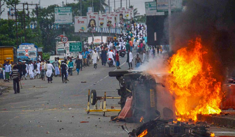 Flames and smoke rise from a vehicle on fire during a protest in Howrah | PTI