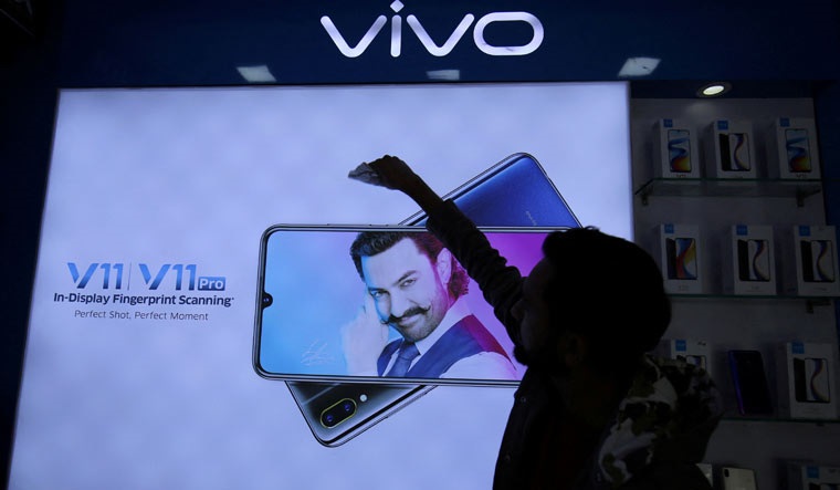 [File] A man cleans a screen displaying a phone model of Chinese smartphone maker Vivo inside a shop in Ahmedabad | Reuters