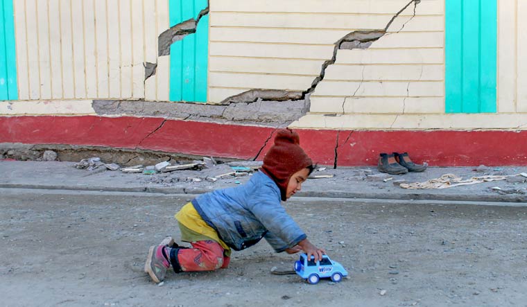 A child plays near a PWD Guest House where cracks appeared due to sinking of land in Joshimath | PTI