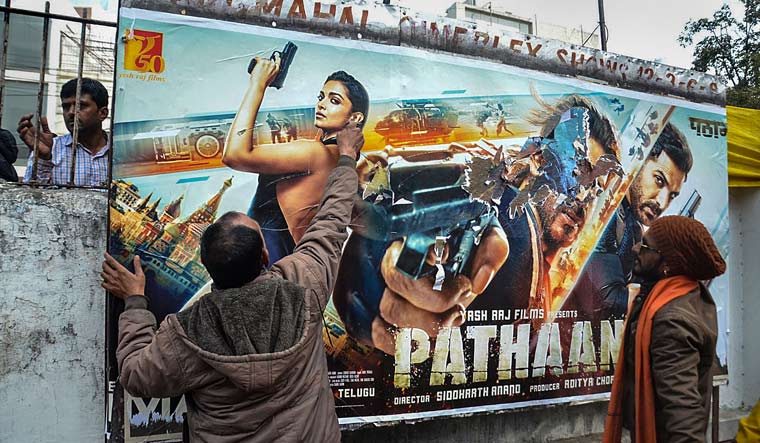 Members of Hindu Jagran Manch tear posters of the newly-released movie 'Pathaan' during a protest, in Bhopal | PTI