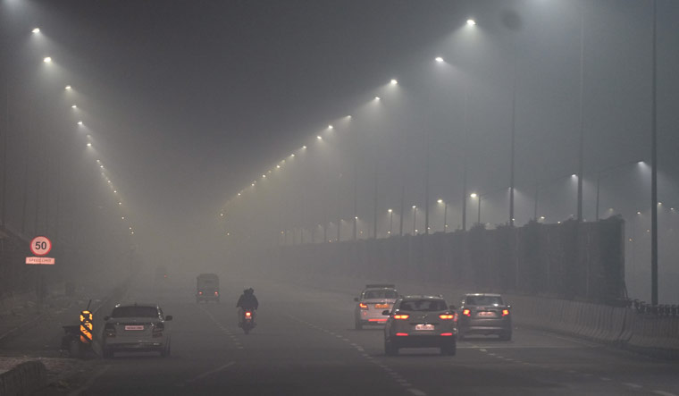 Vehicles move on a road amid low visibility due to smog on Sunday night | PTI