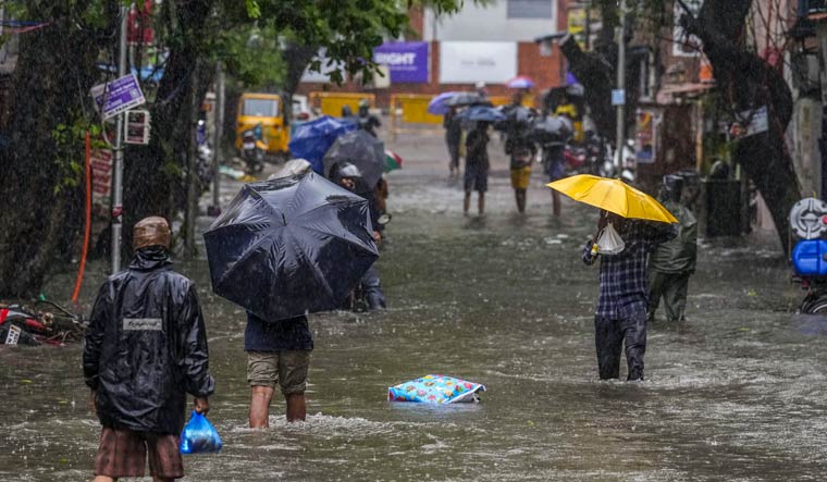 People wade through a waterlogged road in Chennai | PTI
