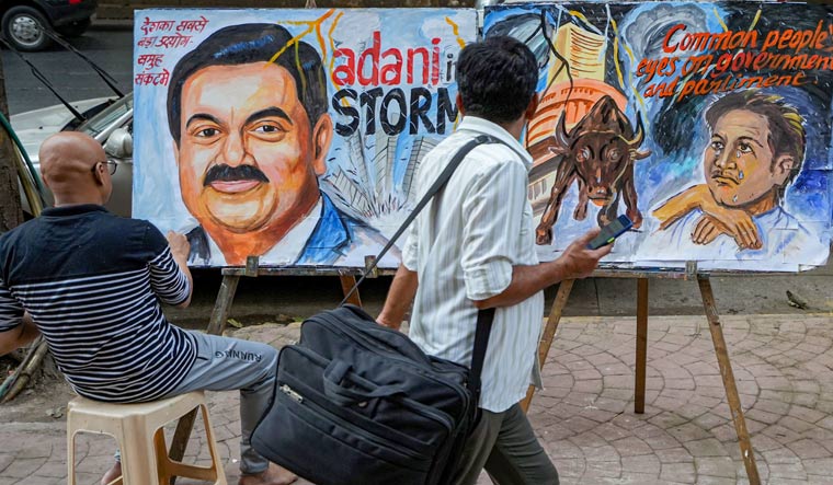 An artist gives final touches to a painting of businessman Gautam Adani highlighting the ongoing crises of the Adani Group, in Mumbai | PTI