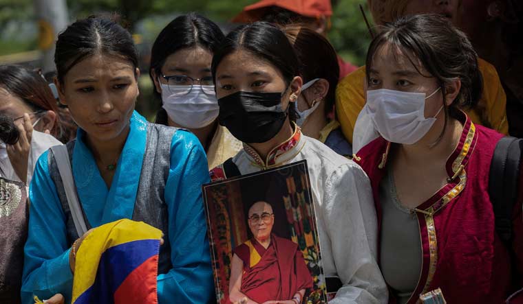 A Tibetan girl holds a picture of their spiritual leader, the Dalai Lama, as they wait for his arrival outside an airport in New Delhi | Reuters