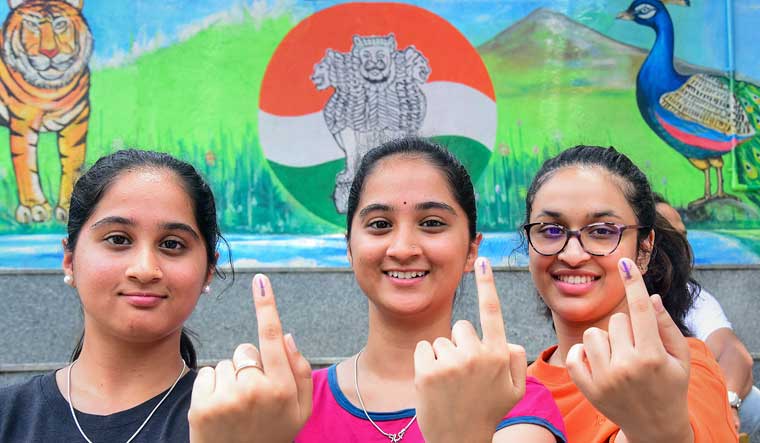 Young women show their inked fingers after casting their votes for the Karnataka Assembly elections, at a polling station in Bengaluru | PTI