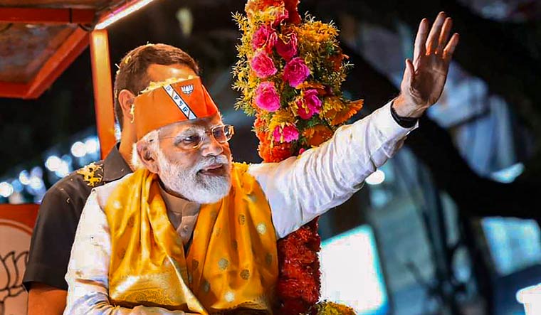 Prime Minister Narendra Modi waves at supporters during an election campaign roadshow in support of BJP candidates ahead of Assembly polls, in Kalaburagi | PTI